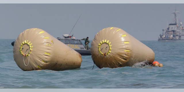 A South Korean Navy Seal member looks at the water while working to rescue missing passengers believed to have been trapped in the sunken ferry Sewol near the buoys which were installed to mark the vessel in the water off the southern coast near Jindo, south of Seoul, South Korea, Sunday, April 20, 2014. After more than three days of frustration and failure, divers on Sunday finally found a way into the submerged ferry off South Korea's southern shore, discovering more than a dozen bodies inside the ship and pushing the confirmed death toll to over four dozen, officials said. (AP Photo/Lee Jin-man)