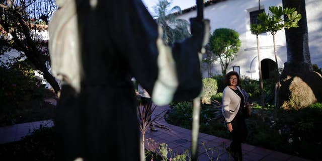 FILE - In this Jan. 27, 2015 file photo, a woman passes a statue of Franciscan missionary Junipero Serra at the Mission San Diego de Acala in San Diego. Pope Francis’ apology for the Roman Catholic Church’s crimes against indigenous peoples has not softened opposition among some California Native Americans to his decision to canonize 18th-century Franciscan missionary Junipero Serra, extolled by the Vatican as a great evangelizer, but denounced by some tribal officials as a destroyer of Native culture. (AP Photo/Gregory Bull, File)