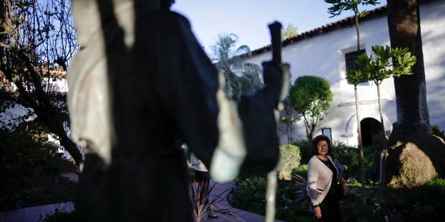 FILE - In this Jan. 27, 2015 file photo, a woman passes a statue of Franciscan missionary Junipero Serra at the Mission San Diego de Acala in San Diego. Pope Francis’ apology for the Roman Catholic Church’s crimes against indigenous peoples has not softened opposition among some California Native Americans to his decision to canonize 18th-century Franciscan missionary Junipero Serra, extolled by the Vatican as a great evangelizer, but denounced by some tribal officials as a destroyer of Native culture. (AP Photo/Gregory Bull, File)