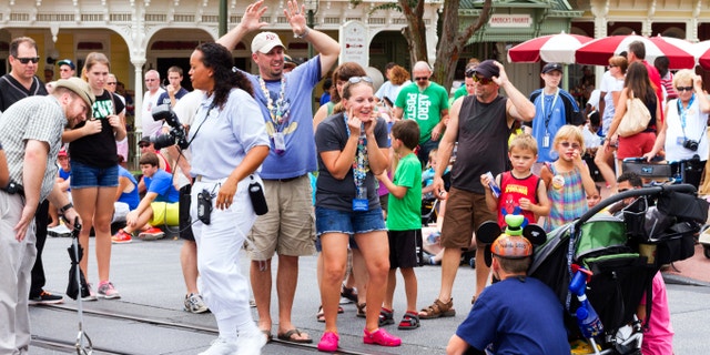 Orlando, USA - August 4, 2013: Parents getting their kids attention for a photo at Main Street USA, the entrance to Magic Kingdom amusement park in Walt Disney World. This is a very popular photo spot as the Cinderella's Caste is in the background.