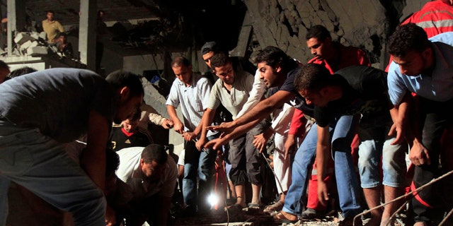 June 19: In this photo taken on a government-organized tour, Libyan firefighters and local residents remove debris from a damaged residential building.