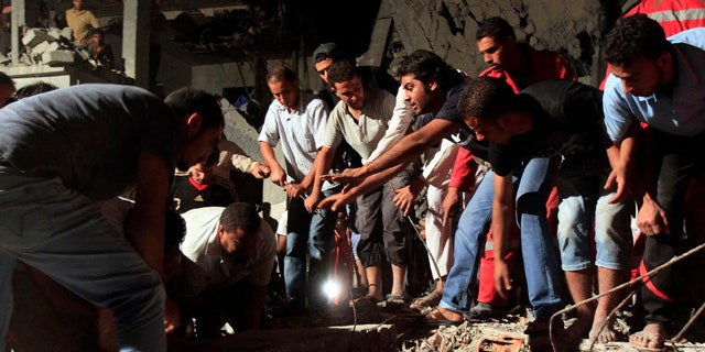 June 19: In this photo taken on a government-organized tour, Libyan firefighters and local residents remove debris from a damaged residential building.