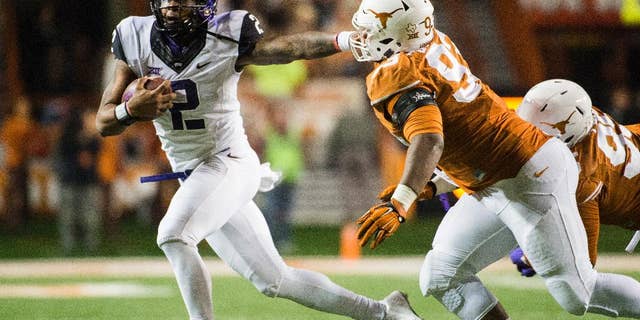 CORRECTS NAME OF TCU PLAYER TO TREVONE BOYKIN - TCU's Trevone Boykin (2) holds off Texas' Paul Boyette Jr. (93) during the second half of an NCAA college football game, Thursday, Nov. 27, 2014, in Austin, Texas. (AP Photo/Ashley Landis)