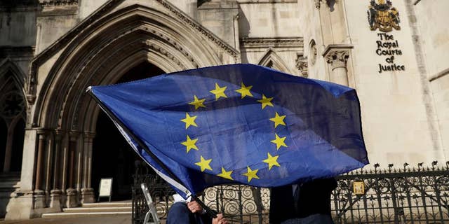 Pro-EU membership supporter Phil Jones holds an EU flag outside the High Court, on the first day of the lawsuit of Gina Miller, a founder of investment management group SCM Private, in London, Thursday, Oct. 13, 2016. Rival protesters have gathered outside the High Court in London, where lawyers are battling over whether the government has the power to trigger Britain's exit from the European Union without approval from Parliament. (AP Photo/Matt Dunham)