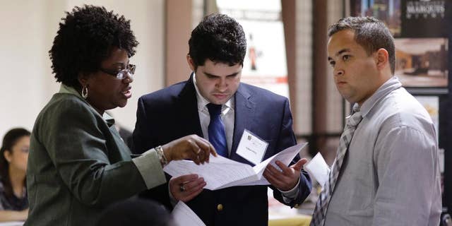 In this Friday, Jan. 23, 2015 photo, instructor Lavinda Young, left, helps Fabian Perez, center, and Lazaro Chaviano, right, with their resumes during a job fair at the Hospitality Institute, in Miami. The U.S. Labor Department reports on the number of people who applied for unemployment benefits for the week ending Jan. 24 on Thursday, Feb. 5, 2015. (AP Photo/Lynne Sladky)