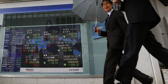 People walk past an electronic stock board showing the global financial index at a securities firm in Tokyo, Thursday, March 24, 2016. Asian stock markets fell for a second day Thursday after declines in prices of oil and other commodities pulled Wall Street lower. (AP Photo/Shuji Kajiyama)