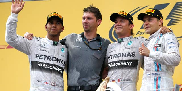Mercedes driver Nico Rosberg of Germany, second from right, celebrates winning on the podium with team member James Vowles, second from left, second placed Mercedes driver Lewis Hamilton of Britain, left and third placed Williams driver Valtteri Bottas of Finland, after the Austrian Formula One Grand Prix race at the Red Bull Ring in Spielberg, Austria, Sunday, June 22, 2014. (AP Photo/Darko Vojinovic)