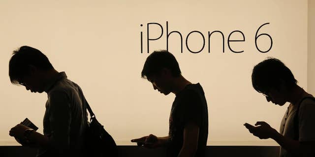 FILE - In this Friday, Sept. 19, 2014, file photo, people wait to buy the new Apple iPhone 6 and 6 Plus devices outside an Apple store in Hong Kong. Apple is embroiled in a Chinese patent dispute that threatens to block future sales of the iPhone 6 in Beijing unless the company can overturn a regulator's recent ruling. The potential ban stems from a decision issued in May 2016 by the Beijing Intellectual Property Office. The agency found the iPhone 6 and iPhone 6 Plus infringed on a Chinese company's patent for the exterior design of its smartphone called the 100C. (AP Photo/Vincent Yu, File)