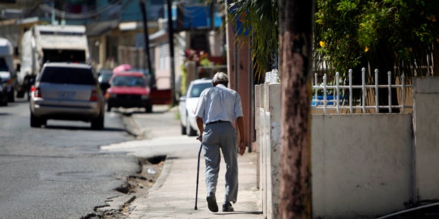 In this Nov. 14, 2013 photo, Mariano Perez Morales, 75, walks a sidewalk in Barceloneta, Puerto Rico.