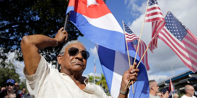 Evilio Ordonez holds Cuban and American flags during a protest against President Barack Obama's plan to normalize relations with Cuba, Saturday, Dec, 20, 2014, in the Little Havana neighborhood of Miami. Florida newspaper editors voted President Barack Obamas mid-December move to normalize relations with Cuba as one of the top stories of the year. (AP Photo/Lynne Sladky)