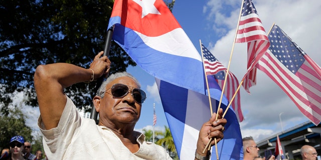 Evilio Ordonez holds Cuban and American flags during a protest against President Barack Obama's plan to normalize relations with Cuba, Saturday, Dec, 20, 2014, in the Little Havana neighborhood of Miami. Florida newspaper editors voted President Barack Obamas mid-December move to normalize relations with Cuba as one of the top stories of the year. (AP Photo/Lynne Sladky)