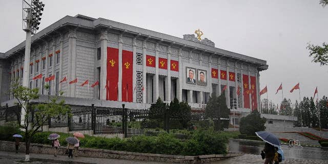 In this Thursday, May 5, 2016, photo, North Koreans walk past the April 25 House of Culture decorated in the colors and flags of their ruling party, Workers' Party, in Pyongyang, North Korea. North Korea’s elite are gathered in Pyongyang ahead of their biggest political conference in decades. Foreign experts say leader Kim Jong Un will likely use the meeting, which starts Friday, to push his expansion of a nuclear arsenal over the strong objections of the U.S., the U.N. and North Korea's neighbors, including ally China. (AP Photo/Wong Maye-E)
