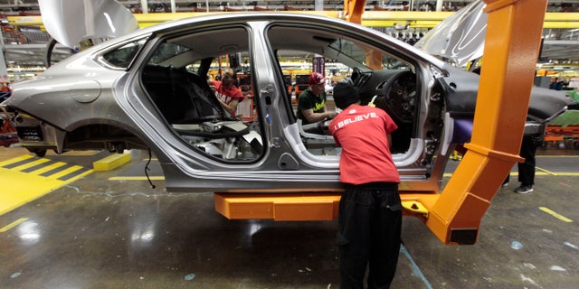 FILE - In this March 14, 2014 photo, assembly line workers build a 2015 Chrysler 200 automobile at the Sterling Heights Assembly Plant in Sterling Heights, Mich. Lured by low wages and tax-saving free trade agreements, auto companies from the U.S. and overseas are accelerating plans to build new factories and add jobs in Mexico. The moves, part of a decade-long trend, are luring investments and work that could have gone to the U.S. and Canada, according to experts. But they also are likely to keep car and truck prices in check even as automakers add expensive fuel-saving features to meet U.S. gas mileage requirements. (AP Photo/Paul Sancya)
