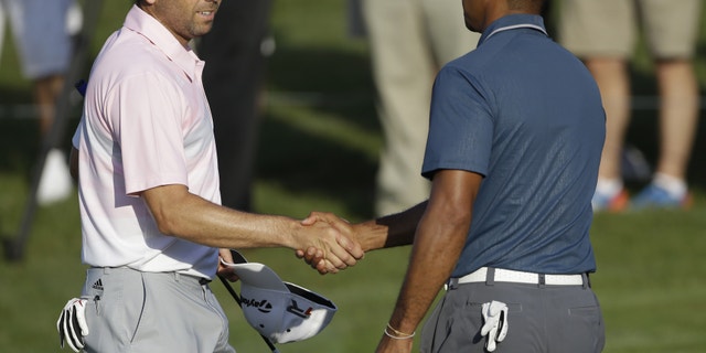 Sergio Garcia, of Spain, left, shakes hands with Tiger Woods at the conclusion of the third round of The Players championship golf tournament at TPC Sawgrass, Sunday, May 12, 2013, in Ponte Vedra Beach, Fla. Play was suspended Saturday due to darkness. (AP Photo/Gerald Herbert)