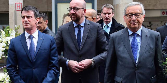 From left, French Prime Minister Manuel Valls, Belgian Prime Minister Charles Michel and European Commission President Jean-Claude Juncker prepare to lay flowers at the Maelbeek metro station in Brussels on Wednesday, March 23, 2016. Belgian authorities were searching Wednesday for a top suspect in the country's deadliest attacks in decades, as the European Union's capital awoke under guard and with limited public transport after scores were killed and injured in bombings on the Brussels airport and a subway station. (Emmanuel Dunand, Pool Photo via AP)