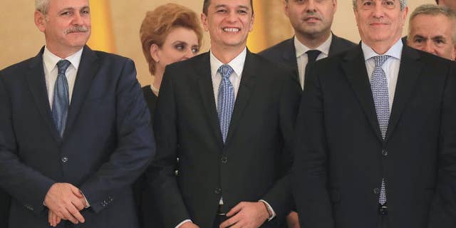 Romanian Prime Minister Sorin Grindeanu, center, smiles while standing between Liviu Dragnea, the leader of the Social Democratic party, left, and Calin Popescu Tariceanu, head of Romania's Senate, after the swearing in ceremony for his cabinet, in Bucharest, Romania, Wednesday, Jan. 4, 2017. Iohannis swore in the new government shortly after it was voted in by parliament, urging it to guarantee an independent justice system and the rule of law, and strengthen its position within the European Union and NATO.(AP Photo/Vadim Ghirda)