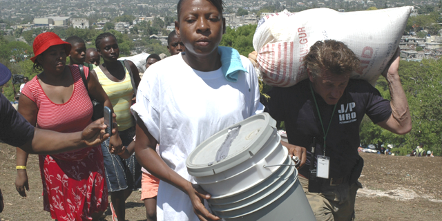 Sean Penn (R) helps to carry the belongings of a earthquake victims during a relocation exercise in Port-au-Prince April 10, 2010. (Reuters)