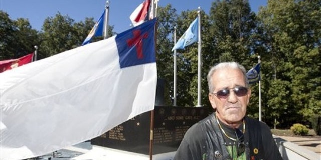 Oct. 16: Ray Martini, an Air Force Veteran, stands beside a Christian flag flying in front of the Veterans Memorial at Central Park in King, N.C. (AP).