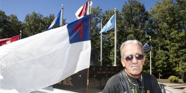 Oct. 16: Ray Martini, an Air Force Veteran, stands beside a Christian flag flying in front of the Veterans Memorial at Central Park in King, N.C. (AP).