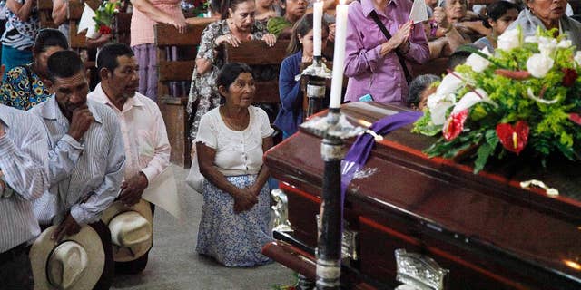 People pray by the coffin of slain Lesbia Janeth Urquia, an environmentalist and indigenous rights activist, during Mass in Marcala, Honduras, Friday, July 8, 2016. Authorities say Urquia's body was found Wednesday in a garbage dump in Marcala. Urquia's assassination comes four months after the murder of award-winning environmentalist Berta Caceres stirred international outrage. (AP Photo/Fernando Antonio)