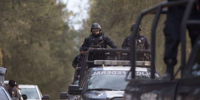 Mexican Federal Police stand guard near the entrance of Rancho del Sol, near Ecuanduero, in western Mexico, Friday, May 22, 2015. At least 43 people died Friday in what authorities described as a fierce, three-hour gunbattle between federal forces and suspected drug gang gunmen at the ranch. (AP Photo/Eduardo Verdugo)