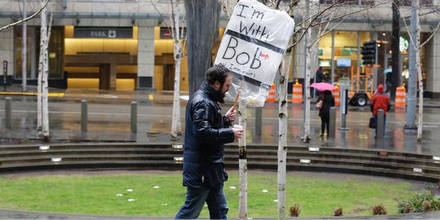 A person walks outside the federal courthouse in Seattle carrying a sign that reads "I'm with Bob and Immigrants," in reference to Washington state Attorney General Bob Ferguson, Friday, Feb. 3, 2017, during a hearing in federal court. A U.S. judge on Friday temporarily blocked President Donald Trump's ban on people from seven predominantly Muslim countries from entering the United States after Washington state and Minnesota urged a nationwide hold on the executive order that has launched legal battles across the country. (AP Photo/Ted S. Warren)