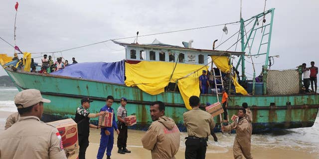 Indonesian officials load food supplies onto a boat carrying Tamil migrants which have been stranded on the beach for the last few days in Lhoknga, Aceh province, Indonesia, Friday, June 17, 2016. Authorities are preparing to tow the boat carryingvdozens of men, women and children out to sea Friday after rescuing it last weekend. (AP Photo/Heri Juanda)