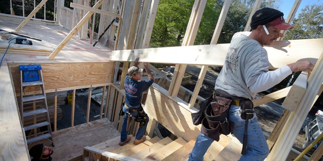 In this Feb. 13, 2015 photo, construction workers James Gibson, left, David Rager, center, and Shawn White frame the second floor of a two-story custom home being built in Orlando, Fla. As construction jobs return in some regions, competition for skilled labor is heating up.(AP Photo/Phelan M. Ebenhack)