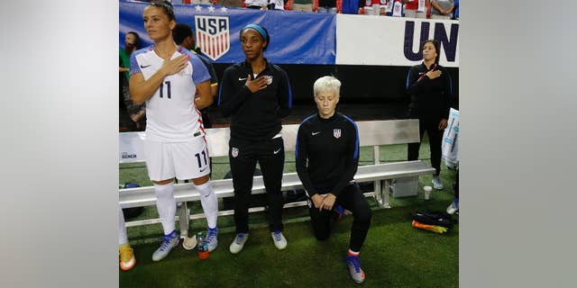 United States' Megan Rapinoe, right, kneels next to teammates Ali Krieger (11) and Crystal Dunn (16) as the U.S. national anthem is played before an exhibition soccer match against Netherlands in Atlanta. (AP Photo)