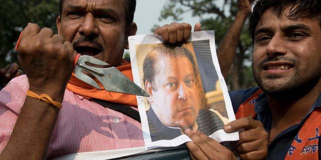 An activist of Hindu nationalist Shiv Sena party points a trident to a photograph of Pakistan Prime Minister Nawaz Sharif as they protest against Sunday's attack at an Indian army base in Kashmir, New Delhi, India, Monday, Sept. 19, 2016. India accuses Pakistan of training the militants in its territory, then helping them to infiltrate into the Indian side. Islamabad denies the charge, saying it only gives political and diplomatic support to the rebels. (AP Photo/Tsering Topgyal)
