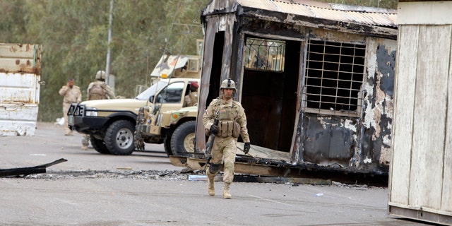 April 8: Iraqi Army soldiers stand guard near burned trailers at Camp Ashraf north of Baghdad, Iraq.