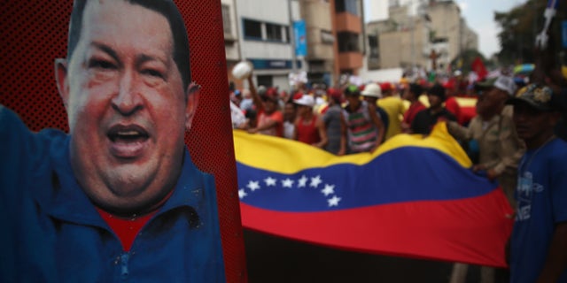 CARACAS, VENEZUELA - MARCH 06: A portrait of former Venezuelan President Hugo Chavez looks on as government supporters march on March 6, 2014 in Caracas, Venezuela. Pro-government organiztions have organized marches in response to widespread opposition demonstrations over the last three weeks. (Photo by John Moore/Getty Images)