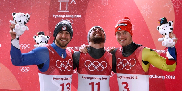 David Gleirscher of Austria, center, celebrates his men's singles luge win with 2nd-place Chris Mazdzer of the U.S. and 3rd-place Johannes Ludwig of Germany.
