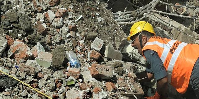An Indian National Disaster Relief Force worker shouts as he looks for survivors in the debris at a building collapse site in Mumbai on September 28, 2013