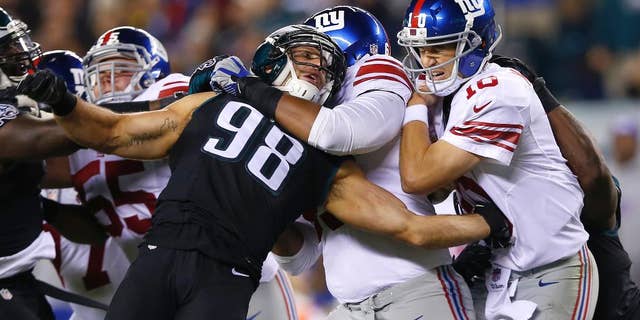 Philadelphia Eagles outside linebacker Connor Barwin (98) is held by New York Giants tackle Will Beatty, center left, as quarterback Eli Manning, center right, is hit by Eagles' Trent Cole, right, after throwing an incomplete pass during the second half of an NFL football game, Sunday, Oct. 12, 2014, in Philadelphia. (AP Photo/Michael Perez)