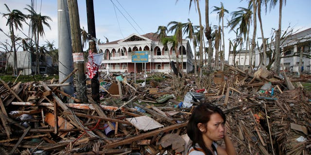 A typhoon survivor walks past the debris-littered Sto. Nino Shrine and Heritage Museum which used to house former Philippine First Lady Imelda Marcos' collection of art pieces from Philippine national artists Sunday Nov. 17, 2013 at Tacloban city, Leyte province in central Philippines. Typhoon Haiyan, one of the most powerful typhoons ever recorded, slammed into central Philippine provinces Nov.8, leaving a wide swath of destruction and thousands of people dead.(AP Photo/Bullit Marquez)