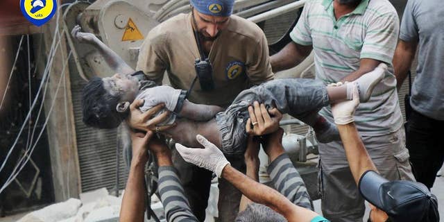 This Tuesday, Sept. 27, 2016 photo, provided by the Syrian Civil Defense group known as the White Helmets, shows a Civil Defense worker carrying the body of a child after airstrikes hit al-Shaar neighborhood in Aleppo, Syria. Pope Francis has decried the assault on the Syrian city of Aleppo, saying those responsible for the bombing must answer to God. (Syrian Civil Defense White Helmets via AP)
