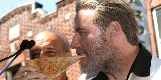 John Travolta, star of "Gotti," eats a slice of pizza in Brooklyn, N.Y., to commemorate his 1970s role in "Saturday Night Fever," June 12, 2018.