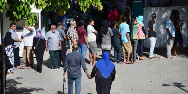 Two Maldivians walk towards the exit of a local polling station after having cast their vote in Male on September 7, 2013