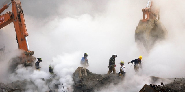 Firefighters walk through clouds of smoke over the ruins of the World Trade Center in New York City on October 11, 2001.  About 3,000 people died when al-Qaeda terrorists hijacked his four planes on September 11, 2001.