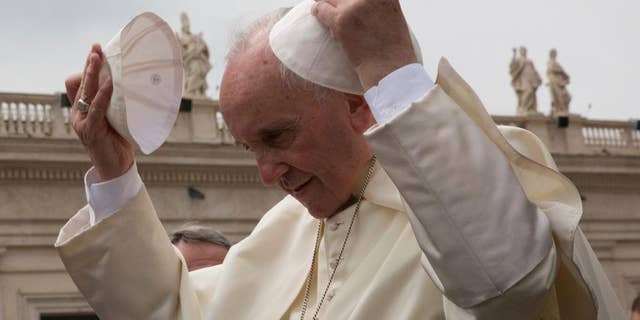 Pope Francis puts on a skull cap given by a worshipper as he leaves after his weekly general audience in St. Peter's Square at the Vatican, Wednesday, May 11, 2016. (AP Photo/Alessandra Tarantino)