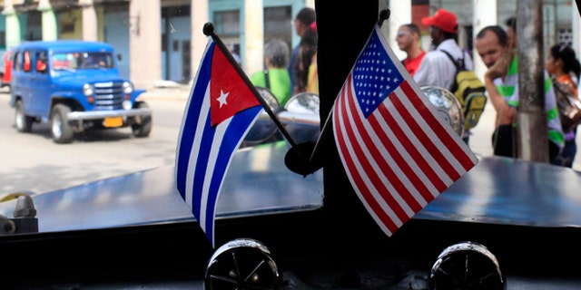 Miniature flags representing Cuba and the U.S. are displayed on the dash of an American classic car in Havana, Cuba, Friday, March 22, 2013. U.S. Secretary of State John Kerry must decide within a few weeks whether to advocate that President Barack Obama should take Cuba off a list of state sponsors of terrorism, a collection of Washington foes that also includes Iran, Syria and Sudan. Cuban officials have long seen the terror designation as unjustified and told visiting American delegations privately in recent weeks that they view Kerry's recommendation as a litmus test for improved ties. (AP Photo/Franklin Reyes)
