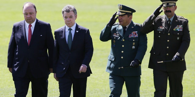 De izquierda a derecha, el ministro colombiano de Defensa, Luis Carlos Villegas; el presidente, Juan Manuel Santos; el comandante de las Fuerzas Armadas Juan Pablo RodrÃguez y el jefe de la policÃa colombiana, Rodolfo Palomino, pasan revista a las tropas durante una ceremonia militar en Bogotá, Colombia, el 9 de julio de 2015. (AP Foto/Fernando Vergara)