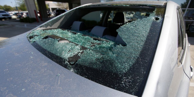 A car damaged by a hail storm sits in a parking lot in Plano, Texas.