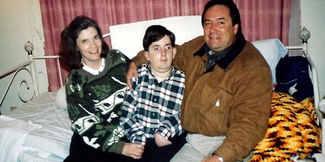 This undated handout photo provided by Paul Cortez shows 15-year-old Mikey Cortez, center, and his parents, Paul and Roonie Cortez. As his 7-year-old son Mikey lay in a hospital bed on life support, the victim of a drunk driver who had smashed into the car he was riding in, Paul Cortez took the boy's hand and made a solemn promise to God: If his son survived, no matter in what condition, he and his family would always be there for him. Although he would never emerge from the persistent vegetative state his father had found him in that night, Mikey's family was not only there for him but also gave him a full life. A life, as it turned out, not all that different from anybody else's, with cross-country family vacations and visits to Disneyland.(AP Photo/Courtesy Cortez Family)