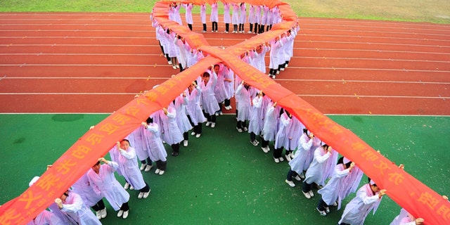 Nurses stand to form a Red Ribbon while holding a banner to mark World AIDS Day at a medical school in Yangzhou, Jiangsu province.