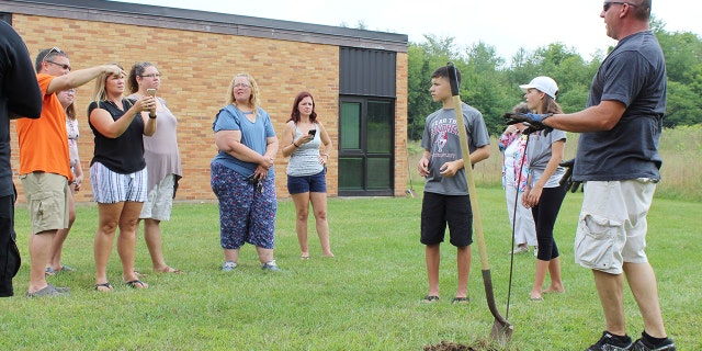 In this Sunday, Aug. 26, 2018, photo classmates that were in the AWARE classes at Coloma Junior High School in 1988 try to find a time capsule that they buried behind the school in Coloma, Mich., that year. The Herald-Palladium reports that the seven classmates and two teachers spent two hours on Sunday digging outside Coloma Junior High in southwestern Michigan.
