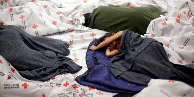 June 18, 2014: Detainees sleep in a holding cell at a U.S. Customs and Border Protection processing facility in Brownsville,Texas. (AP Photo/Eric Gay, Pool)