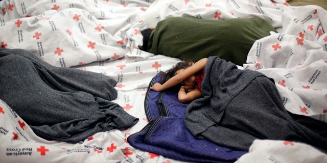 June 18, 2014: Detainees sleep in a holding cell at a U.S. Customs and Border Protection processing facility in Brownsville,Texas. (AP Photo/Eric Gay, Pool)