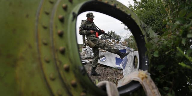 AP10ThingsToSee- A Pro-Russian rebel looks at pieces of the Malaysia Airlines Flight 17 plane near village of Rozsypne, eastern Ukraine, Tuesday, Sept. 9, 2014. The Dutch team investigating the downing of Malaysia Airlines Flight 17 over Eastern Ukraine says the crash was likely caused by the plane being hit by multiple "high-energy objects from outside the aircraft." (AP Photo/Sergei Grits)